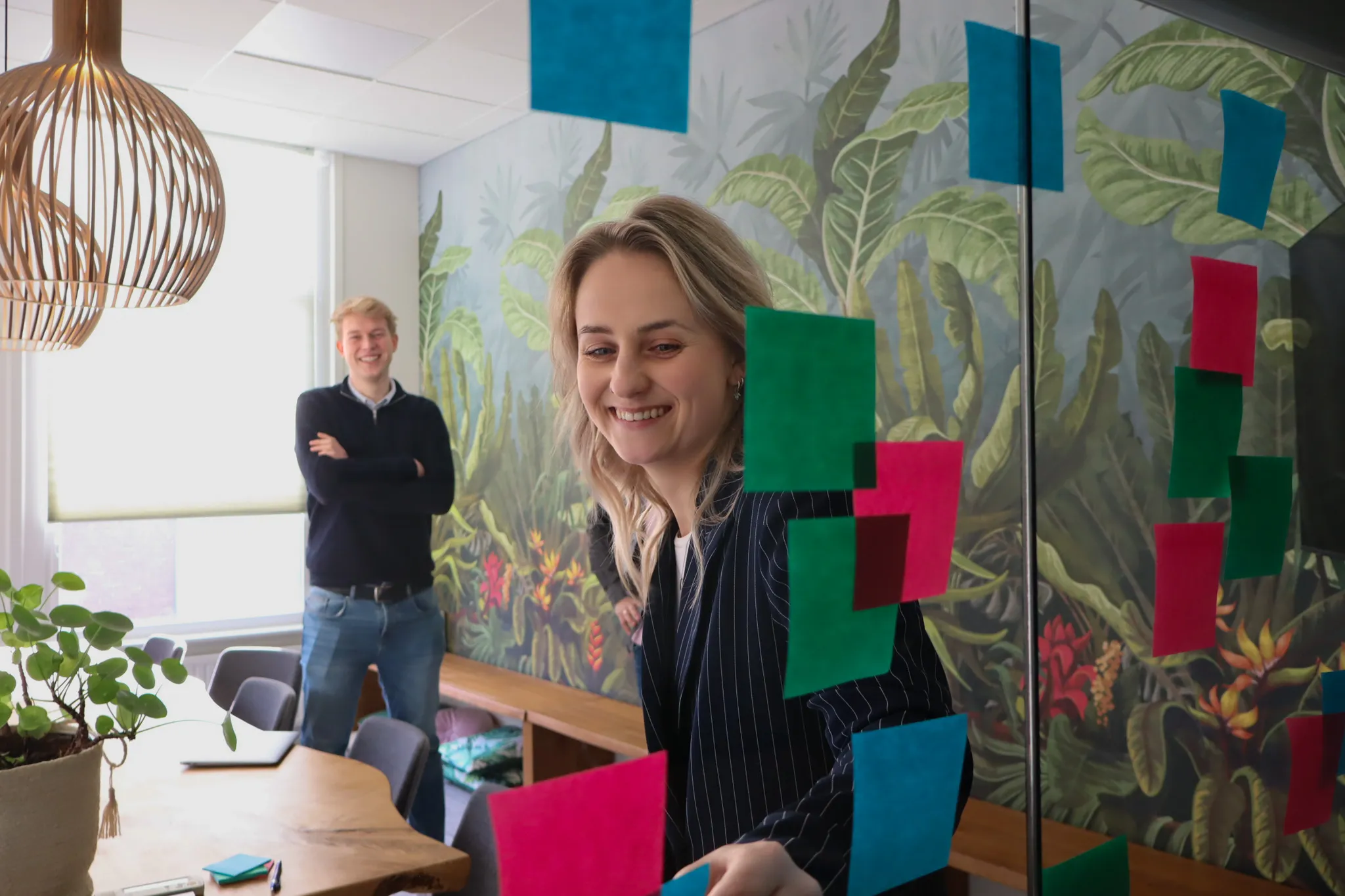 Teamsessie met gekleurde post-its op een glazen wand